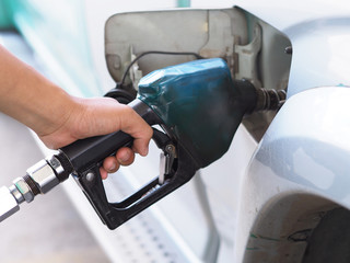 Close up hand of man pumping gasoline fuel in car at gas station.