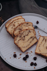 Slices of homemade vanilla stirred pound cake baked in loaf pan with cinnamon sugar and hazelnut marble swirls on rustic sheet or tray with crumbs fresh from the oven on dark background