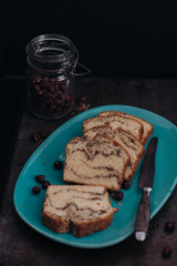 Slices of homemade vanilla stirred pound cake baked in loaf pan with cinnamon sugar and hazelnut marble swirls on rustic sheet or tray with crumbs fresh from the oven on dark background