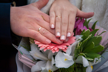 hands of the bride and groom on a bouquet of flowers