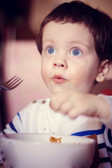 The boy eats himself from the plate. An independent child. The child eats