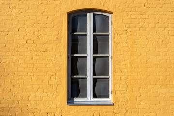 window on yellow painted brick wall