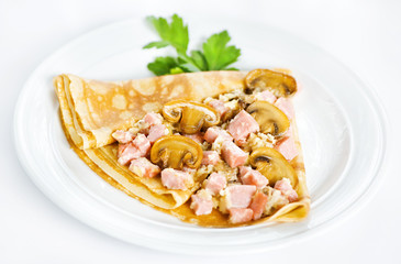 Thin delicious pancake with ham and mushrooms on white