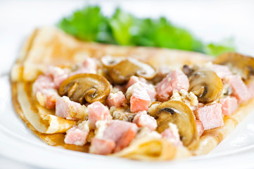 Thin delicious pancake with ham and mushrooms on white
