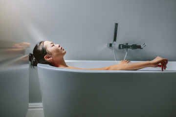 Asian female lying in bathtub