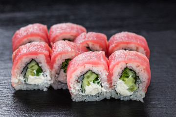 Philadelphia makizushi roll with tuna arranged on stone background