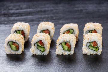 Vegeterian makizushi roll with cucumber and tomato arranged on slate plate background