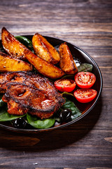 Grilled steak with potatoes and vegetables on wooden table