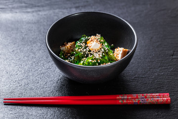 Seaweed salad with tofu seasoned with unagi sauce with pair of chopsticks