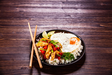 Grilled meat, white rice,fried egg vegetables on wooden table