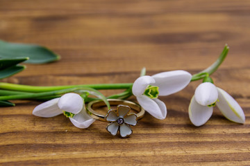 Golden ring and snowdrops on wooden background