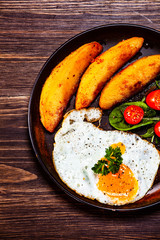 Fried egg, baked potatoes and vegetables