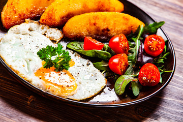Fried egg, baked potatoes and vegetables