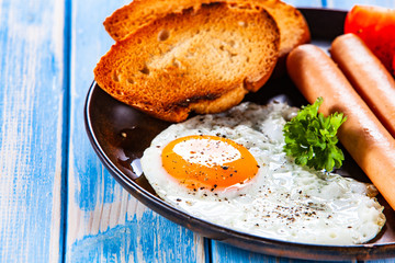 English breakfast - fried egg, sausages, toasts and vegetables