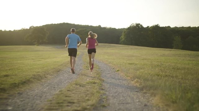 4K following couple jogging in dry grassland in summer