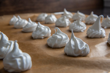 Closeup on raw meringue cookies on brown baking paper detailed 