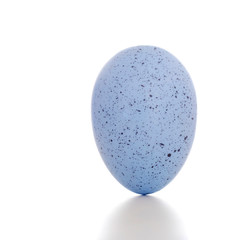 Blue painted egg, standing upright, on white background with shadow.