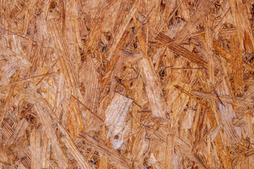 OSB boards are made of brown wood chips sanded into a wooden background. Top view of OSB wood veneer background, tight, seamless surfaces
