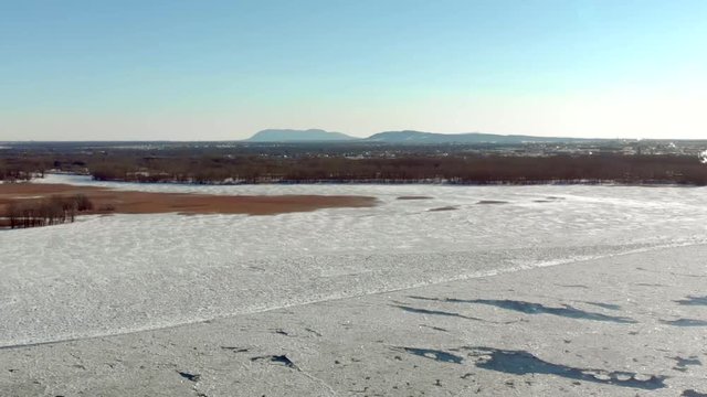 Aerial view of frozen river moving at the end of winter slow motion