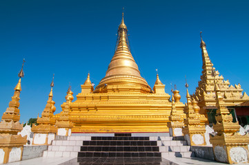 Golden Sandamuni Pagoda with row of white pagodas. Amazing architecture of Buddhist Temples at Mandalay, Myanmar.