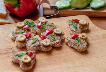 heart shaped canape with liver pate, decorated with olives, sweet peppers and dill, cooking at home, close up