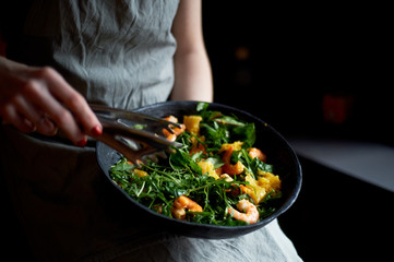 Healthy diet. Salad of arugula, tiger prawns and oranges. Light dish with seafood. Diet menu. Hands...