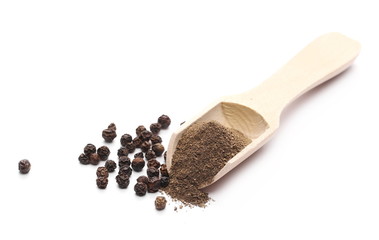 Black pepper grains and powder with wooden spoon isolated on white background
