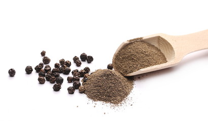 Black pepper grains and powder with wooden spoon isolated on white background