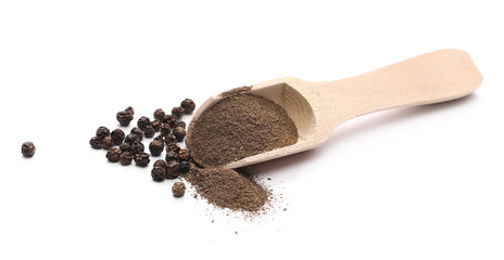 Black pepper grains and powder with wooden spoon isolated on white background