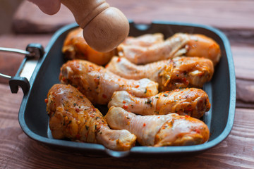 Raw chicken drumsticks in sauce and spices in a pan not a wooden background.