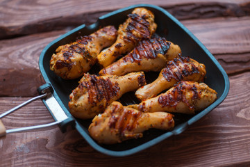 Chicken drumsticks cooked with spices on a grill pan.