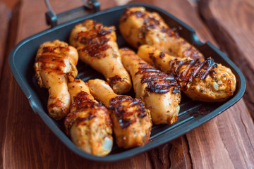 Chicken drumsticks cooked with spices on a grill pan.
