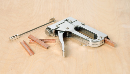 construction stapler, staples on wooden background