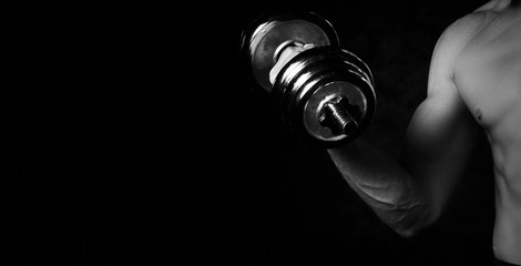 Part of man's body with metal dumbbell on a dark background