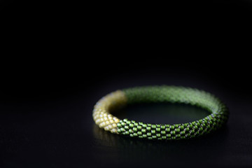 Bead crochet bracelet two shades of green on a dark background close up