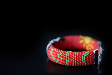 Red bracelet with funny panda on a dark background close up