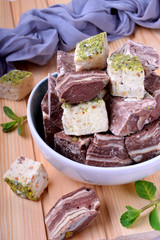 Halva and sherbet in a bowl against the wooden background. Assortment of oriental desserts