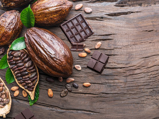 Cocoa pod, cocoa beans and chocolate on the wooden table. Top view.