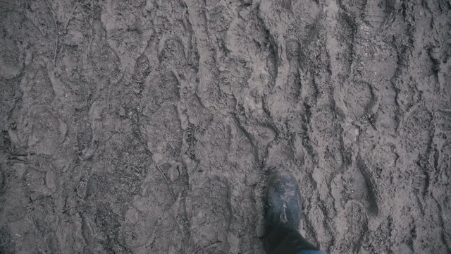 Muddy boots walking along a muddy path in slow motion