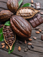 Cocoa pod, cocoa beans and chocolate on the wooden table. Top view.