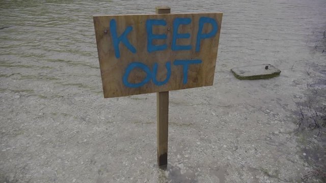 Wooden keep out sign on a lake in slow motion