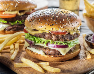 Hamburgers and French fries on the wooden tray.