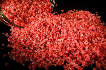 closeup big pink organic sea salt poured out from small glass jar