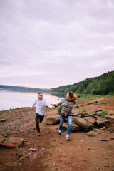 Young couple having fun and running along the river