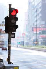 A vertical shot of a red traffic light signal on a bright, hazy day with no people. Nathan Road, Hong Kong.