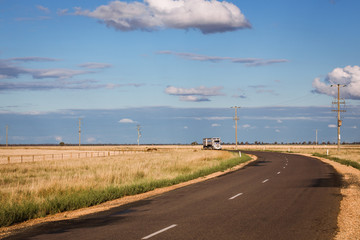 A curved outback road with an approaching truck in rural Australia on a sunny afternoon.  Copy space.