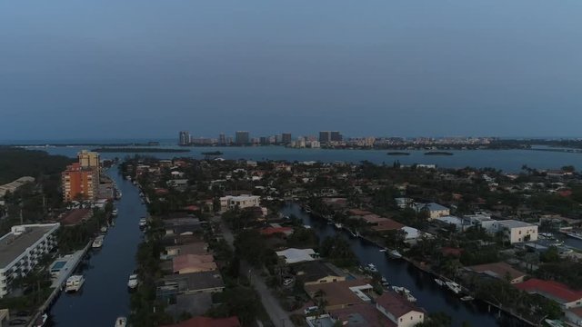 Aerial shot flying near houses in North Miami with buildings on the coast in the background