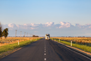 A truck approaches on a long, straight single lane highway in rural New South Wales.