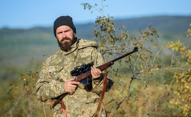 Hunting is brutal masculine hobby. Man aiming target nature background. Hunter hold rifle. Aiming...