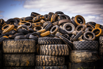 Pile of old used car and truck tyres in a tire dump against an afternoon sky.  Victoria.